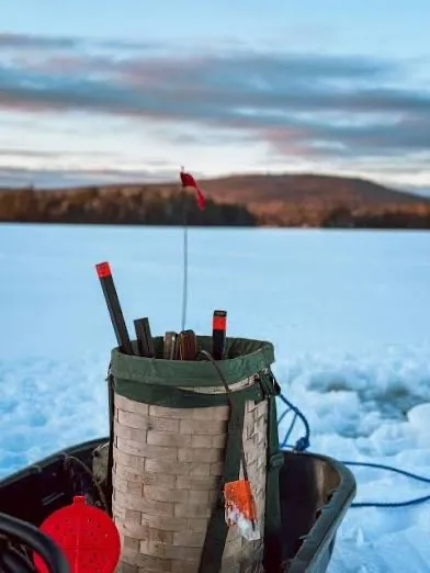 Ice fishing on a frozen Maine lake at sunset