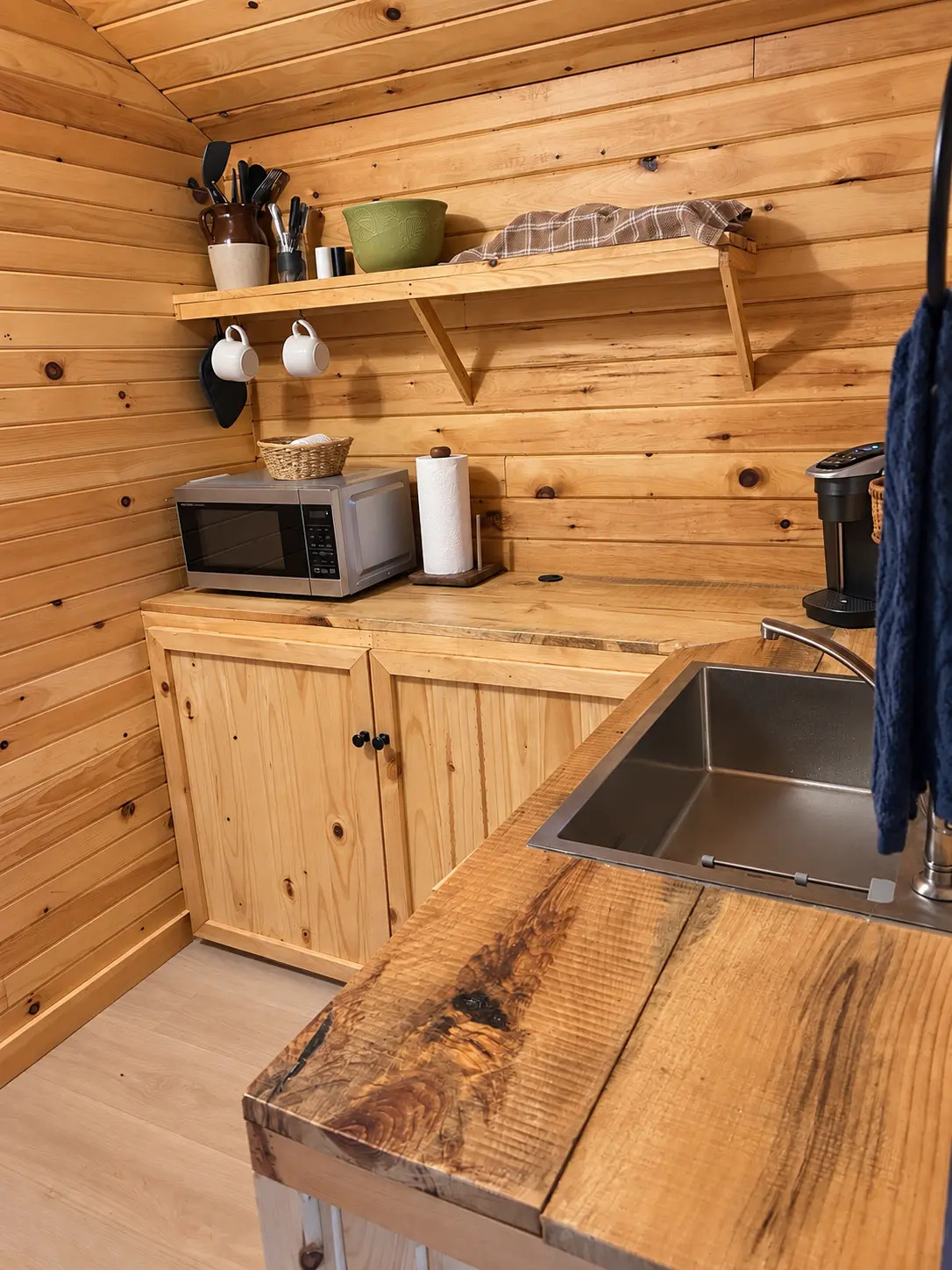 Kitchenette with a stainless sink, microwave and open shelving